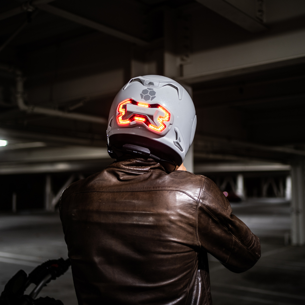 Rider putting on his white Arai helmet with white Brake Free mounted on the back of the helmet.